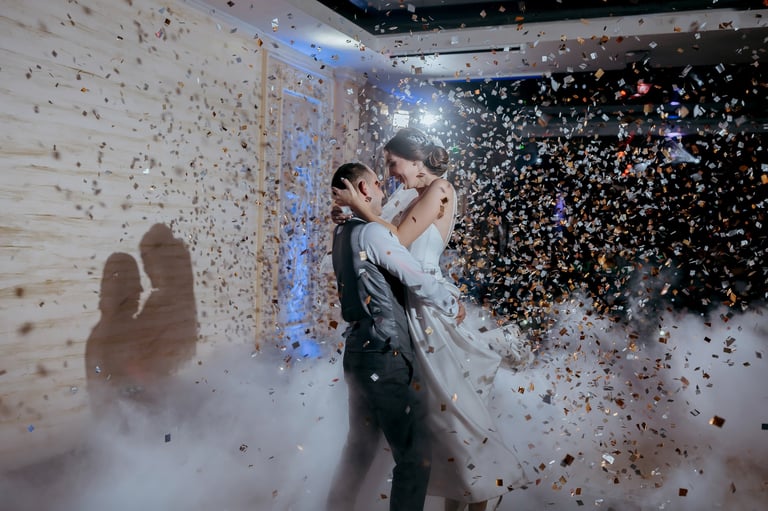 Couple dancing with golden confetti falling at their wedding celebration