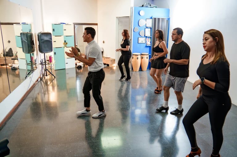 Adults learning dance moves from an instructor in a studio